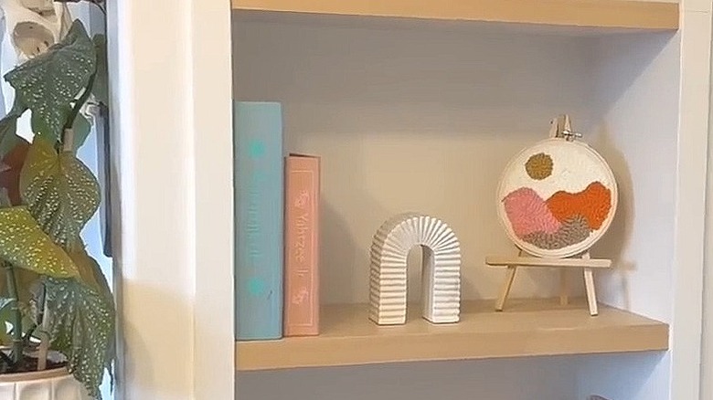 Two board games stored in DIY book boxes on a shelf next to artwork