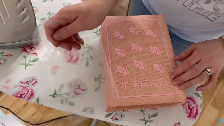 Two board games stored in DIY book boxes on a shelf next to artwork