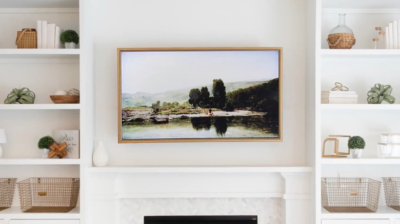 TV surrounded by a custom frame displayed above a fireplace and between shelves