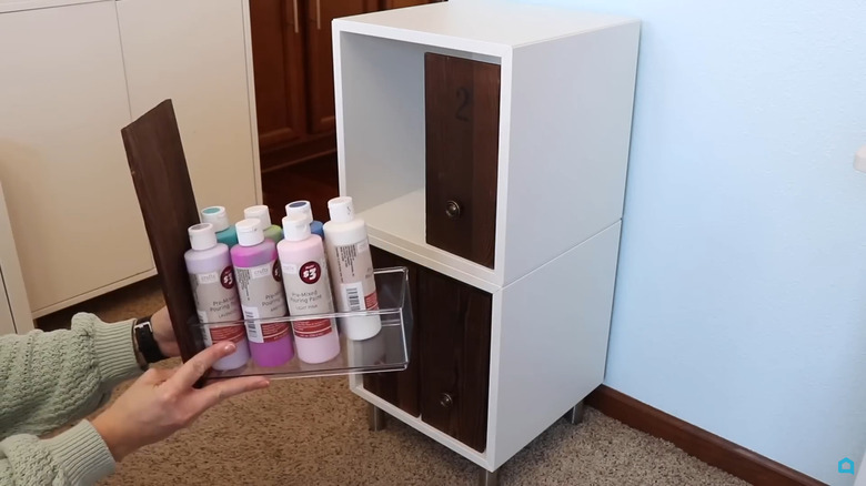 Person pulling out a storage container with the wood front hiding the contents
