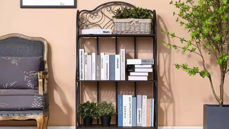 Three-tiered bronze bakers rack in a living room with books and plants on it