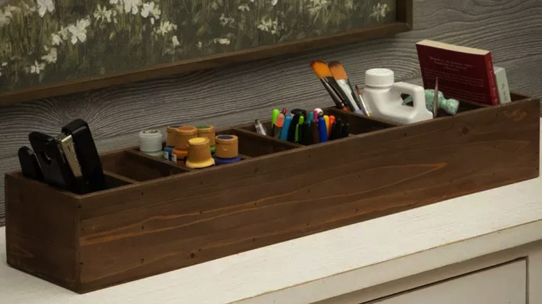 divided wood box on a white dresser filled with craft and office supplies