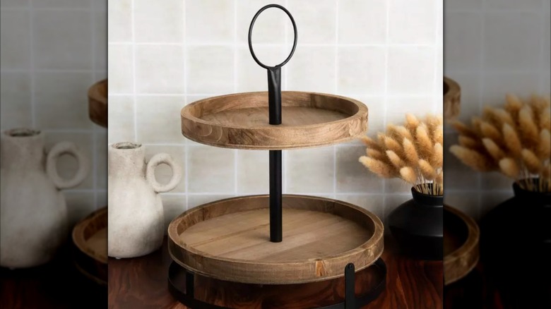 tiered wood tray on a counter with pottery near it