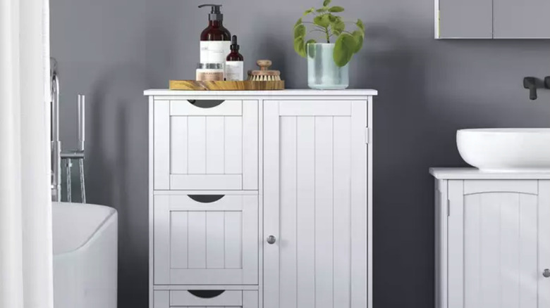 white cabinet with drawers in a bathroom with toiletries and a potted plant on top