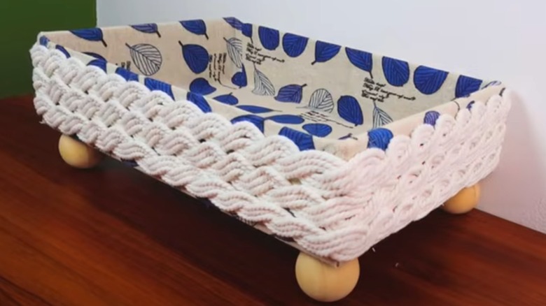 In tray decorated with fabric, string and four big beads as legs