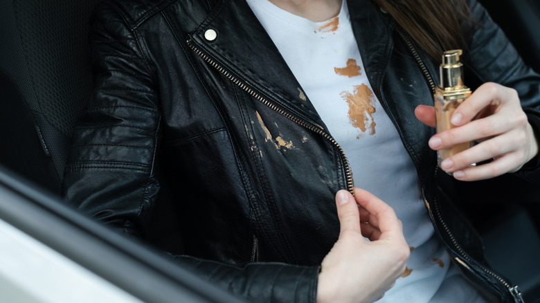 A woman wearing a black leather jacket and white t-shirt with make up foundation stains on them.
