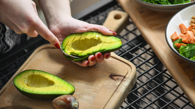 person cutting and peeling avocado