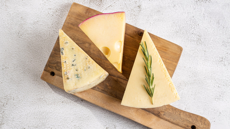three cheese wedges on cutting board