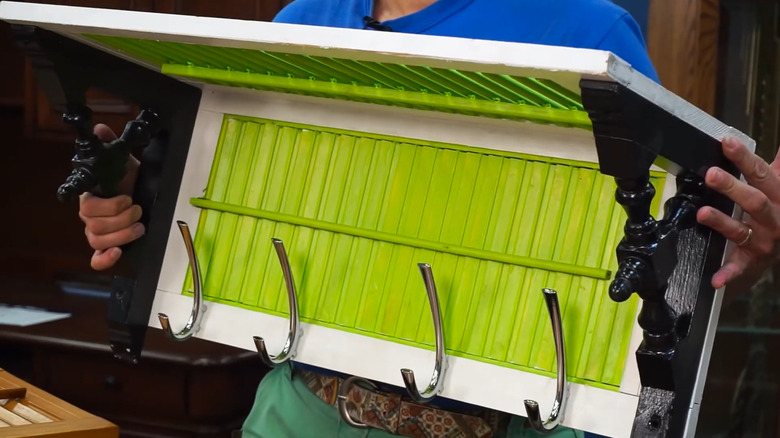 Person holding a shelf made of two shutters and brackets with hooks added