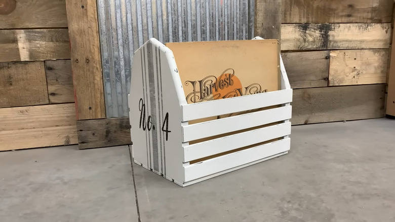 Wood magazine rack painted white with stripes and lettering, holding old vinyl records with a rustic background