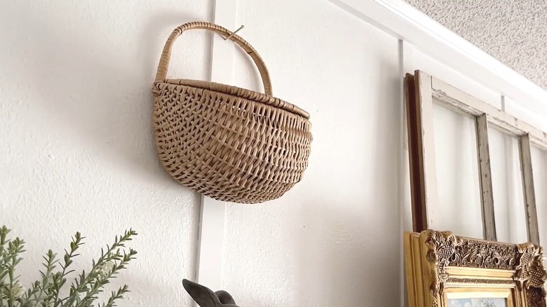 Basket with a lid hanging from a nail on the wall by its handle