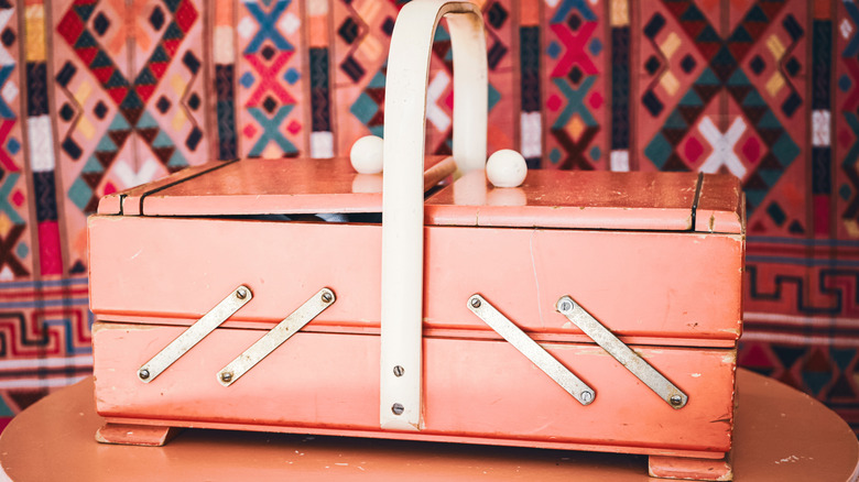 A vintage wooden cantilever sewing box with metal braces that allow trays to swing up and outward