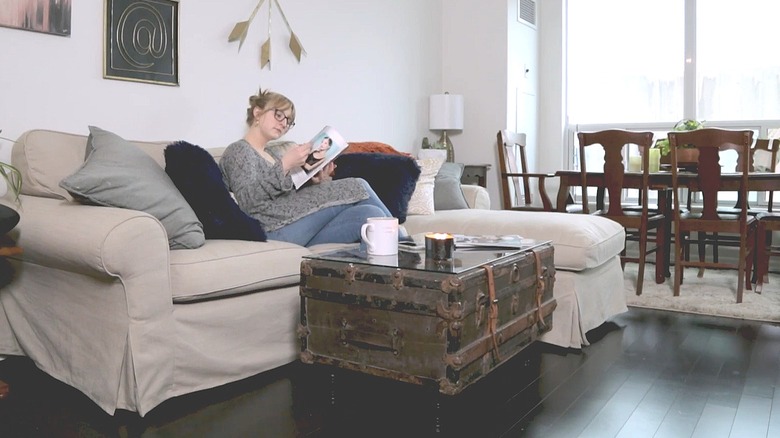 Woman sitting on a sectional next to an old trunk upcycled into a coffee table