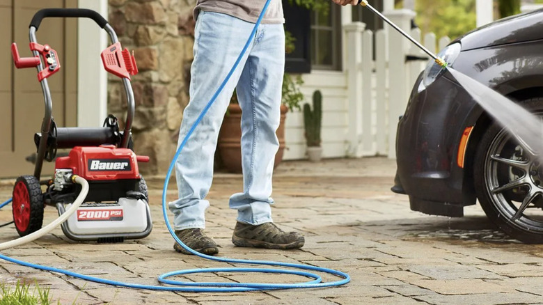 A man uses a pressure washer with a 25-foot hose to wash his car
