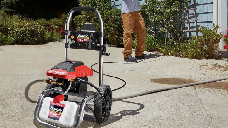 A man uses a Baur's 2300 PSI electric pressure washer to wash the siding on his home
