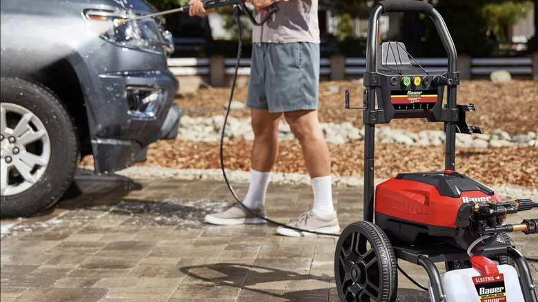 A man uses Baur's 3000 PSI pressure washer to clean the front of a truck