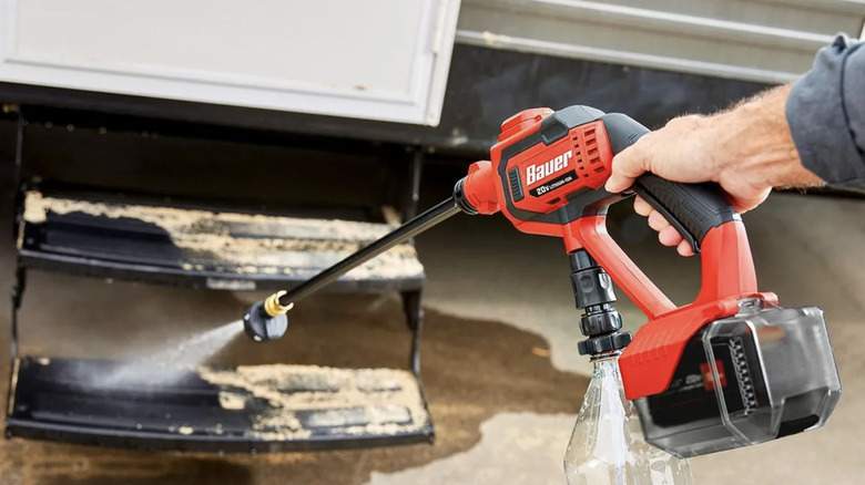 A man uses Baur's portable power cleaner to wash RV stairs