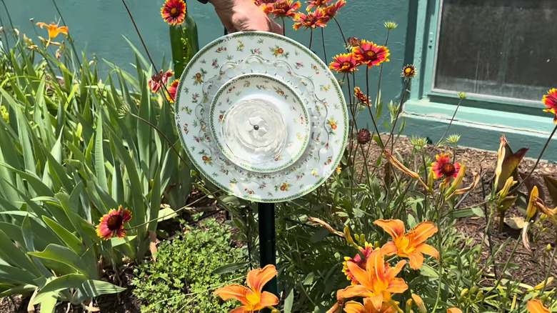 Garden flower decoration made from a large plate, smaller plate, and bowl in a flower bed