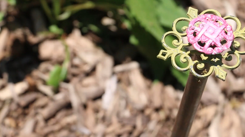 Close-up of a decorative hose guard in a garden with a mulch background