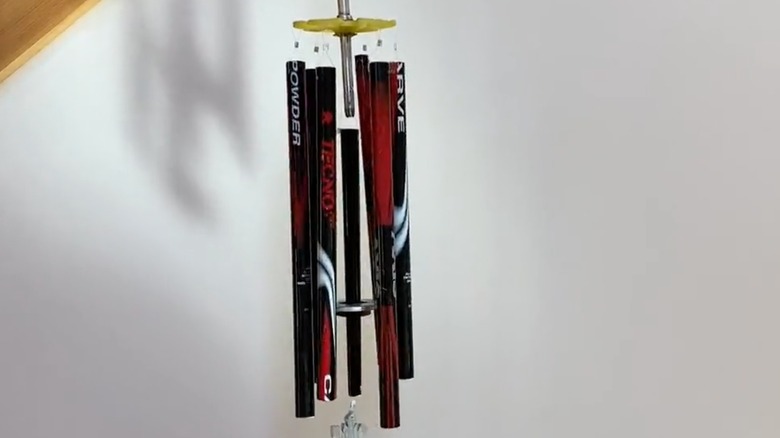 A black and red ski pole wind chime with snowflake decoration.