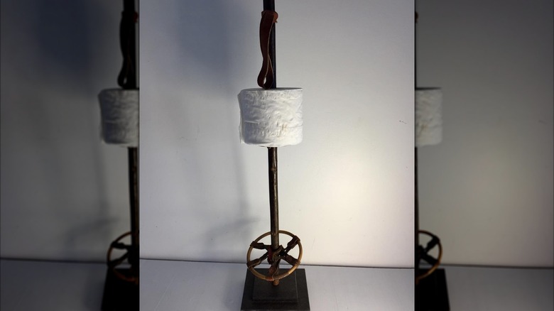 A ski pole toilet paper holder with a roll on it.