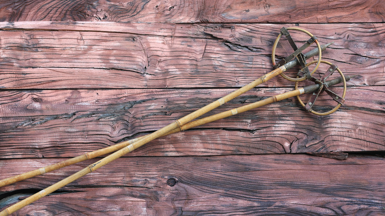 Two vintage bamboo ski poles on wood background.