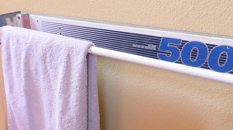 A ski pole towel rack on wall with towel hanging off.