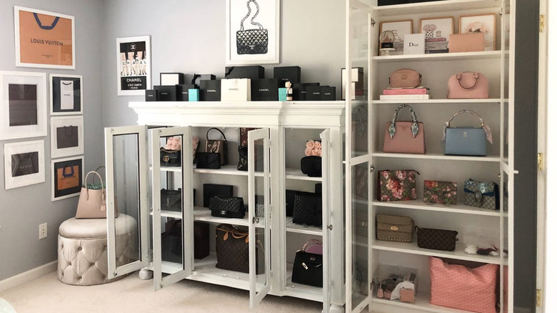 white bookshelves with doors holding a collection of purses