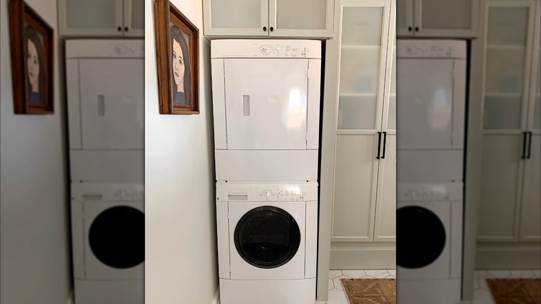 gray billy bookcase with doors next to white stacked dryer and washer