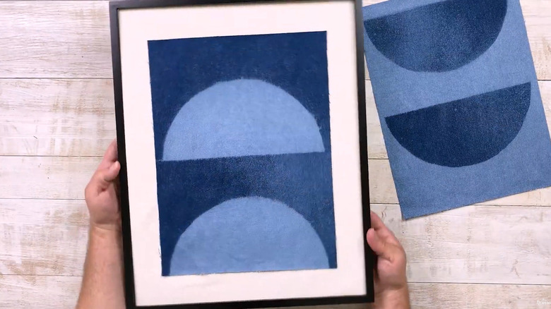 Person holding a framed bleached denim piece