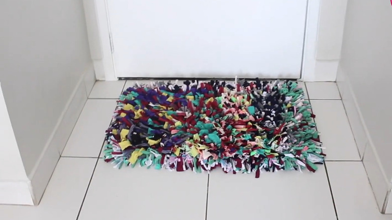 Shag rug made from strips of various-colored T-shirts sitting on the floor by a door