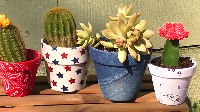 Flower pots covered in assorted red, white, and blue fabrics with succulents planted in them