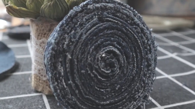 Close-up of a DIY coaster made from a rolled-up denim seam