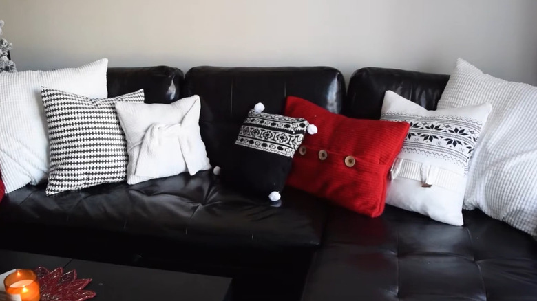 Multiple throw pillows with DIY sweater covers propped up on a black sofa