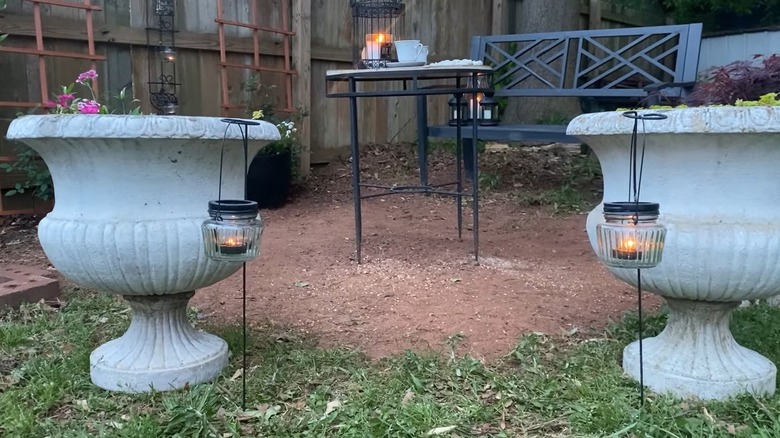 Lanterns in garden near huge white planters and one on a black table