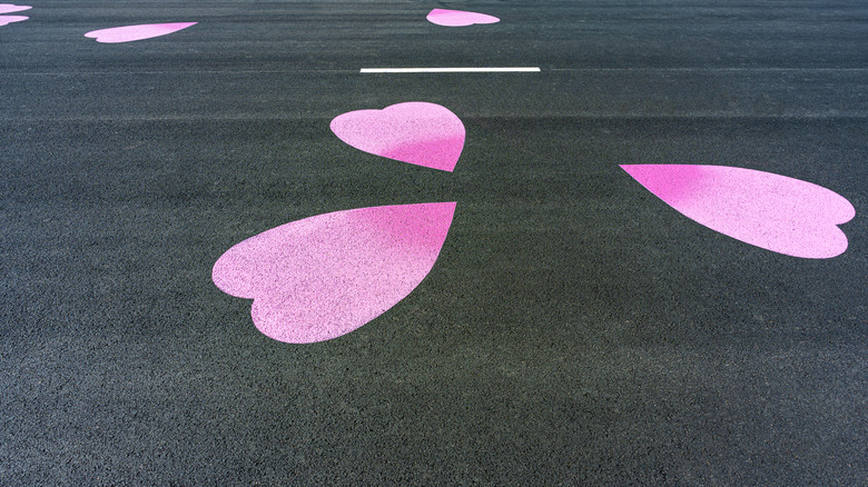 Pink hearts stenciled on a black-painted concrete driveway.