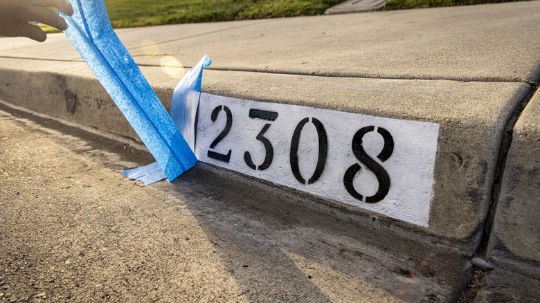 A house number painted on driveway curb.