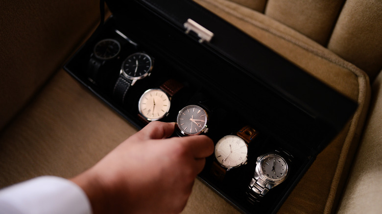 A hand picking out expensive watches from a case