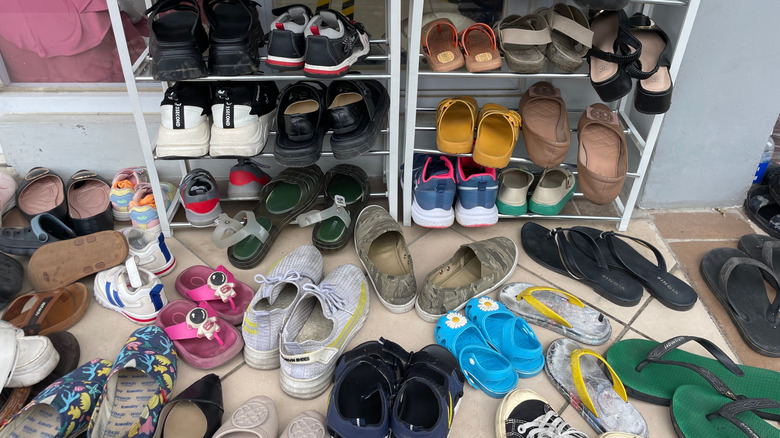 Dozens of shoes on a rack and on the floor in a home
