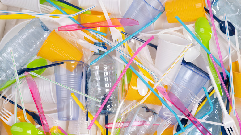 A pile of single-use items including spoons, cups, water bottles, and straws