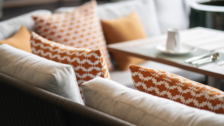 Several colorful and patterened throw pillows on a couch, as seen from the back of a couch
