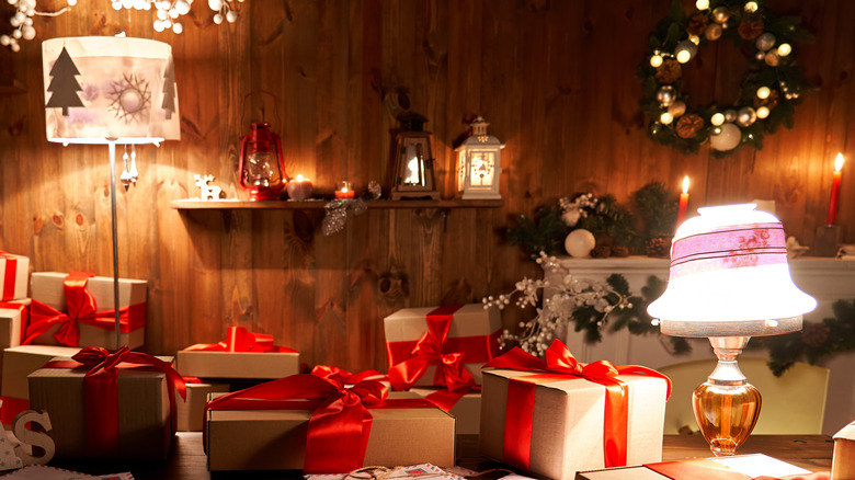 Holiday presents spread across a table with a vintage table lamp, tall floor lamp, and mini lantern