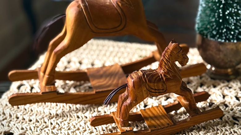 Miniature wooden rocking horses next to a mini Christmas tree