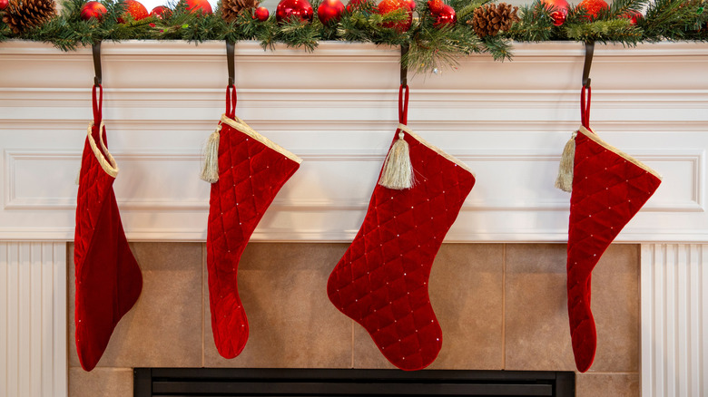 Classic red velvet-looking stockings with ornate gold detailing hanging on a mantel
