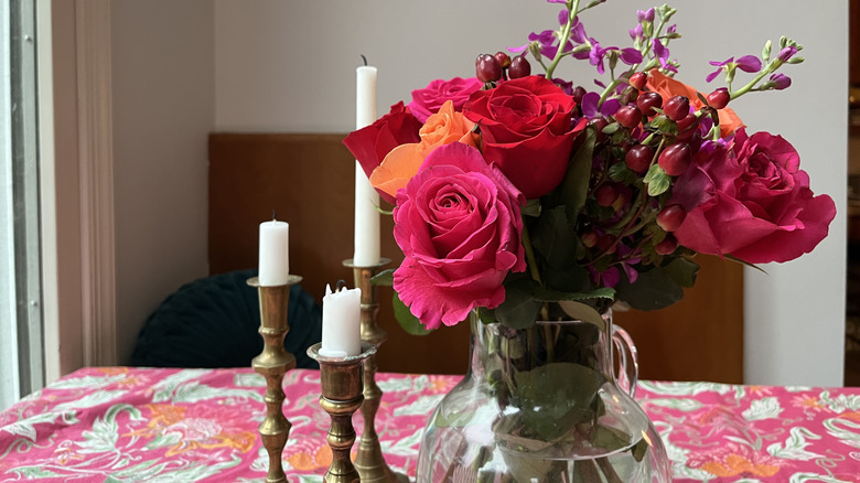 brass candlesticks next to flowers on table