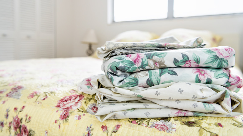 stack of vintage floral sheets on bed