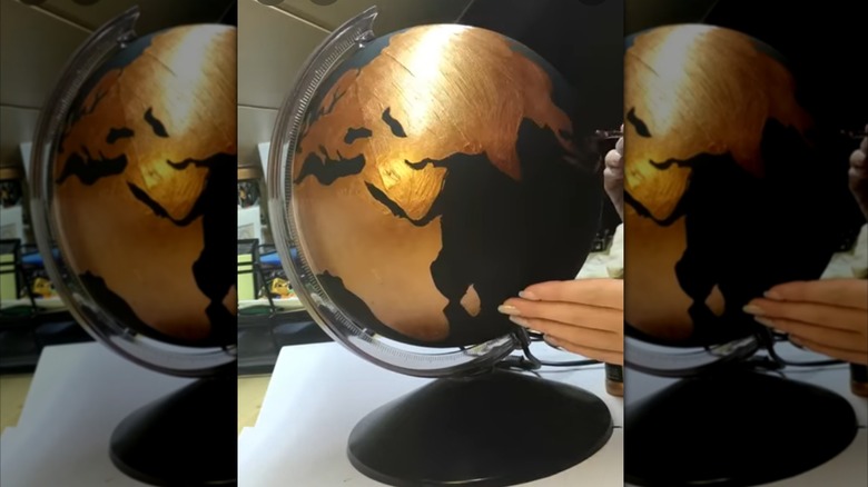 A black and gold painted globe on a stand