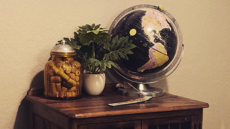 A black globe sitting on a wood table next to a plant