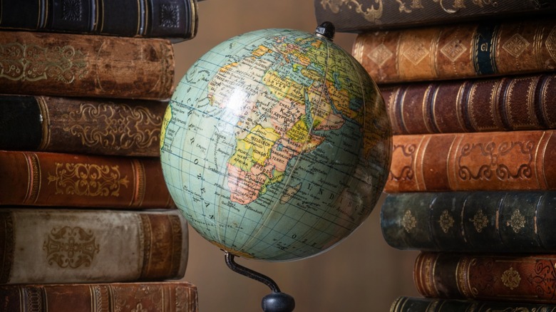 A globe on a stand surrounded by old books