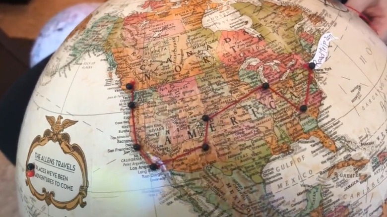 A globe with pins and ribbon showing a road trip